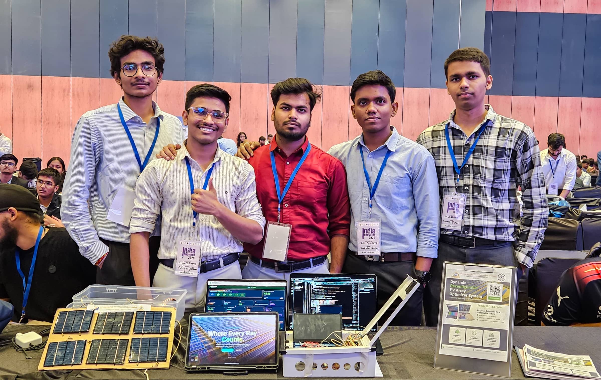 India Innovates team behind a table displaying solar panels, electronics and project screens
